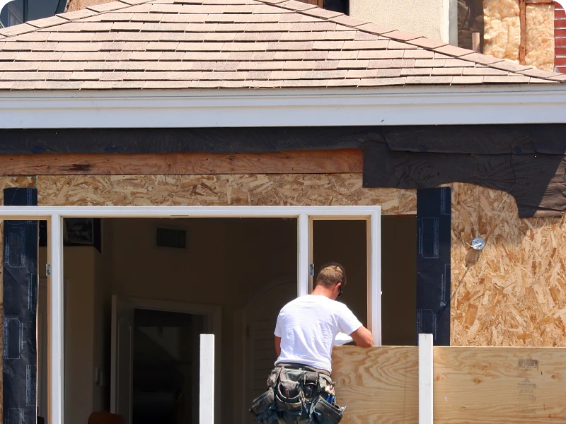 Worker renovating house exterior with plywood